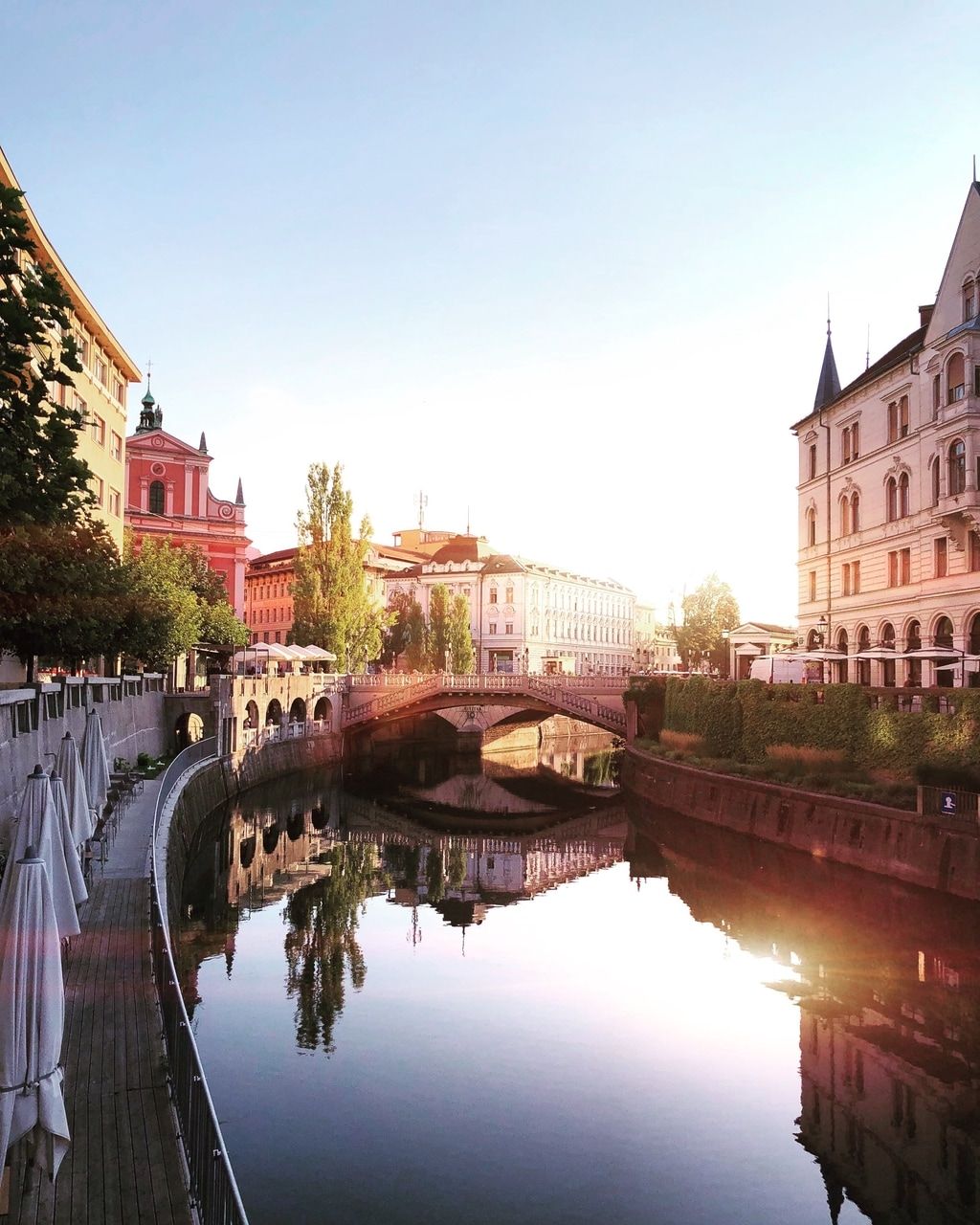 Vista del río al amanecer en una ciudad con edificios históricos y un puente.